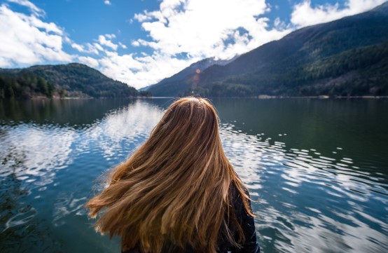 Person with long hair looking over lake